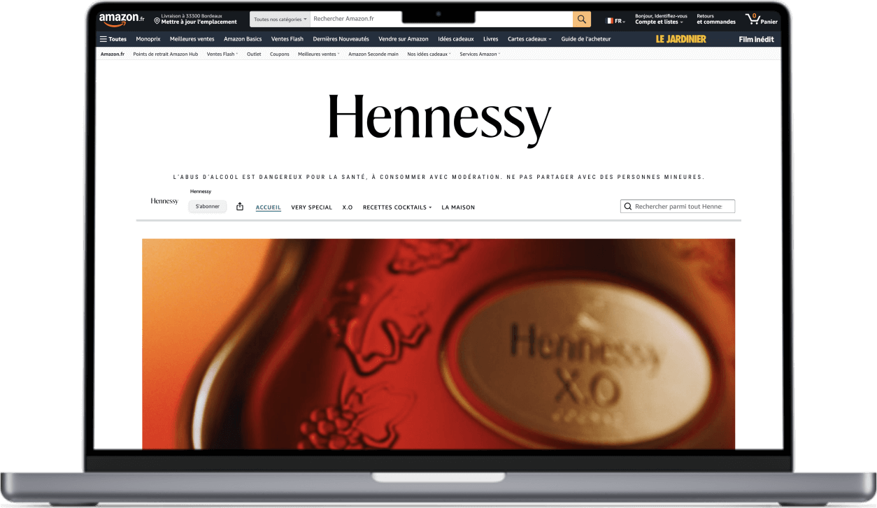 Superchouette- Un ordinateur portable affiche la page d'accueil du site Hennessy, avec une image en gros plan d'une bouteille Hennessy X.O. et des menus de navigation en haut.